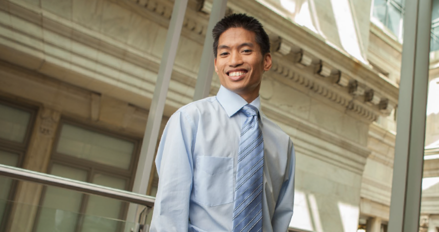 An asian man in business attire smiling at the camera.